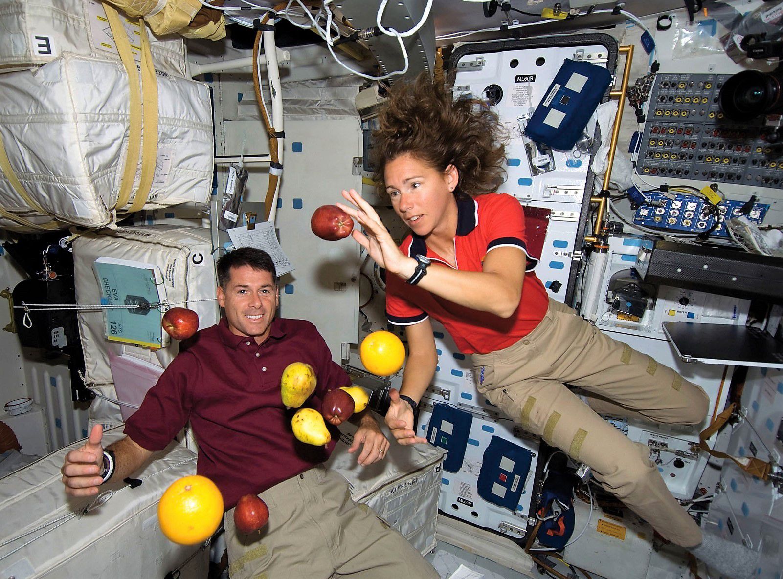Een man en een vrouw met zwevend fruit in een cockpit.
