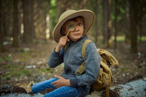 Kind met vergrootglas en rugzak in het bos